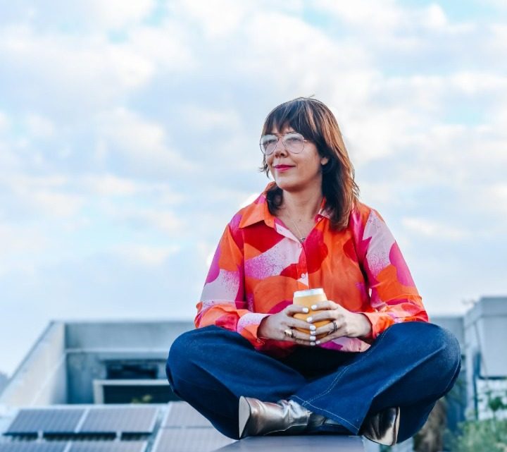 Karla sitting cross-legged on her building's rooftop beside the solar panels